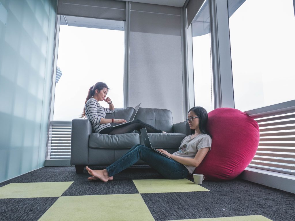 Two women sitting, working on their computers